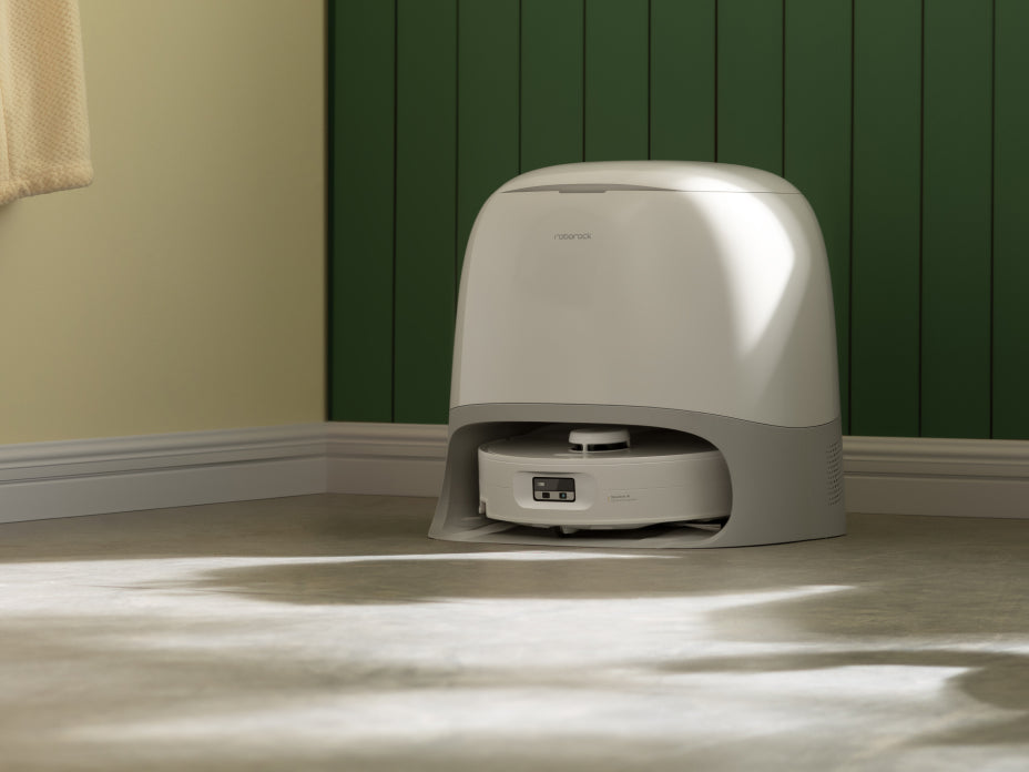 White Roborock Qrevo Curv 2 Flow robot vacuum docked in a curved white base station against a green paneled wall