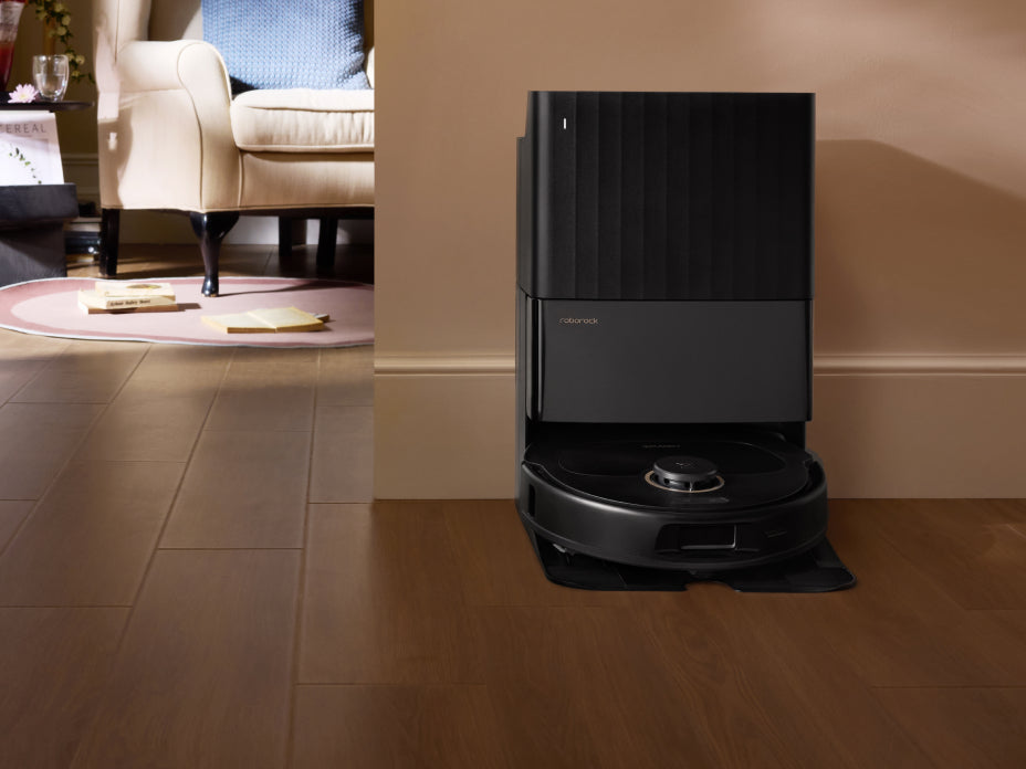 Black Roborock Qrevo S5V robot vacuum docked in a tall black base station on a wooden floor in a living room setting