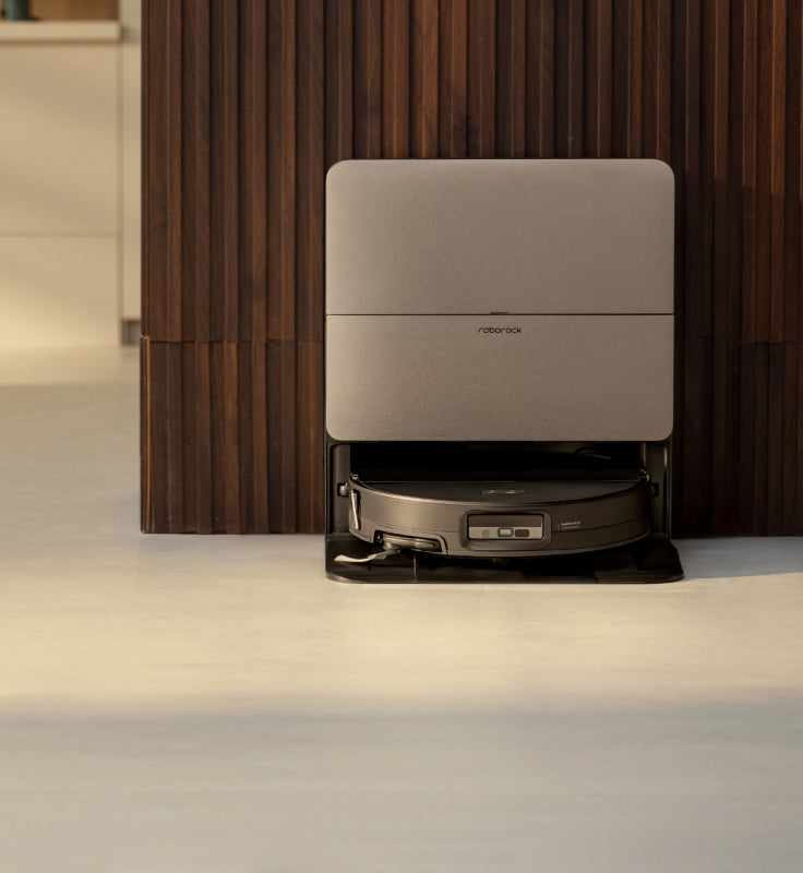 Black Roborock Q10 S5+ robot vacuum docked in a black base station on a wooden floor